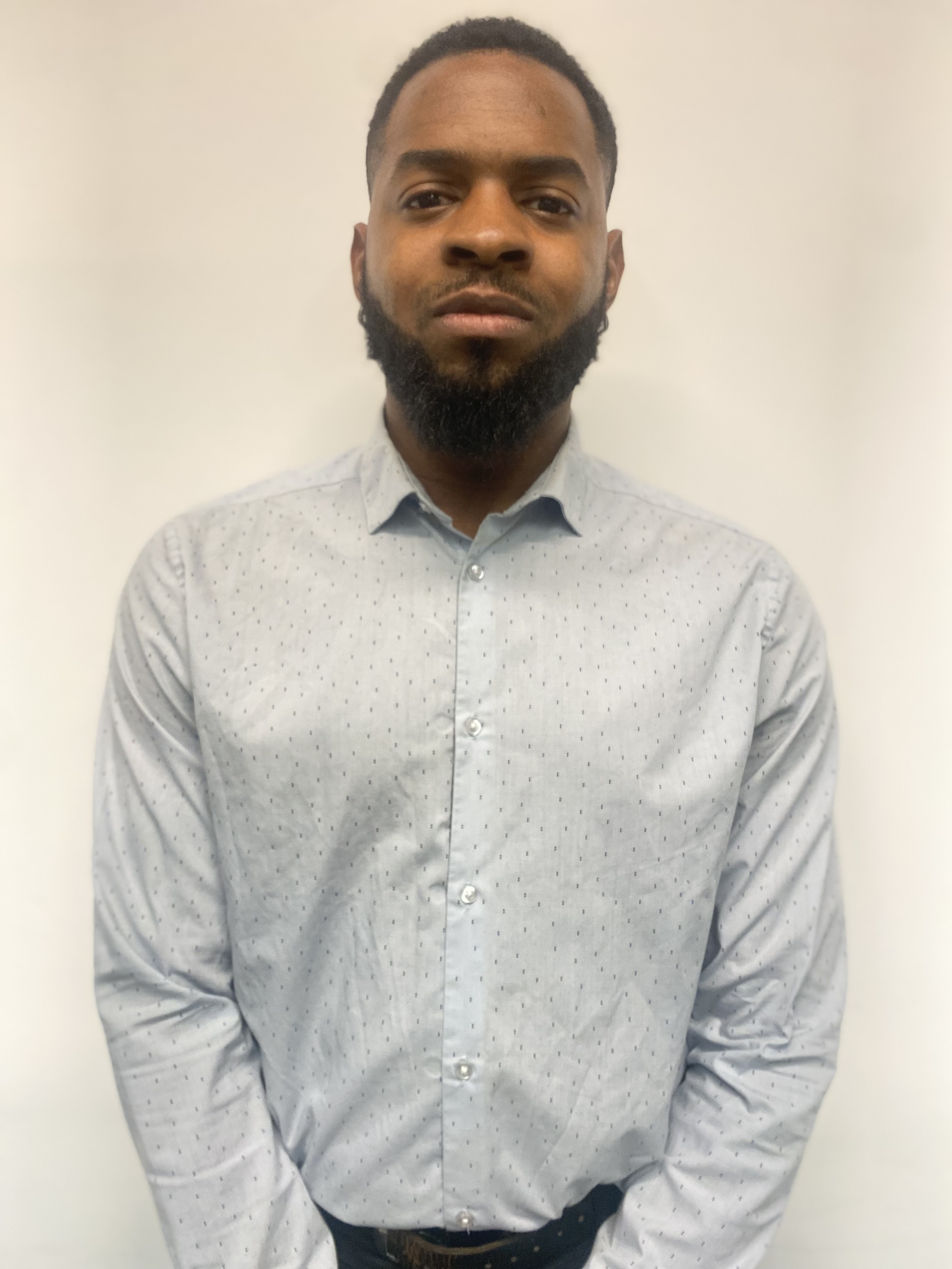Daryl Cointre standing before a wall in a blue shirt